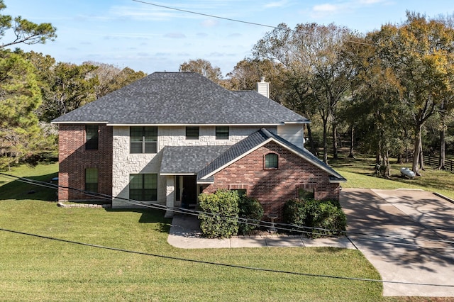 traditional-style home featuring roof with shingles, a chimney, a front yard, and brick siding
