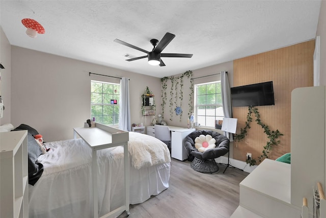 31235 Edgewater Dr, Magnolia, TX 77354 - bedroom with light wood-type flooring, wood walls, a textured ceiling, and ceiling fan