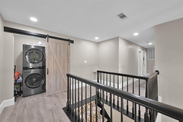 31235 Edgewater Dr, Magnolia, TX 77354 - washroom with stacked washer / drying machine, wood finished floors, baseboards, a barn door, and recessed lighting