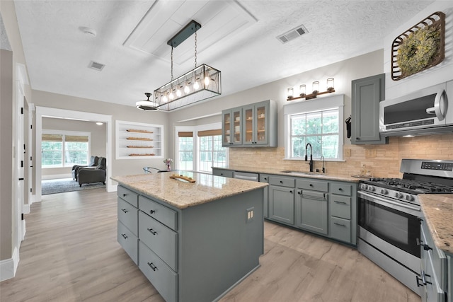 kitchen featuring a sink, visible vents, gray cabinetry, stainless steel appliances, and light wood finished floors