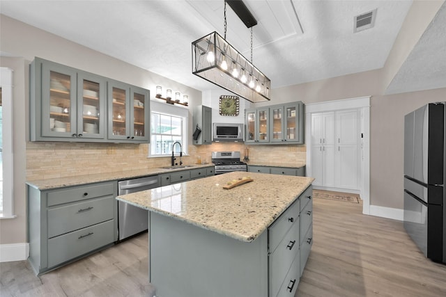31235 Edgewater Dr, Magnolia, TX 77354 - kitchen featuring appliances with stainless steel finishes, gray cabinets, a sink, and decorative backsplash