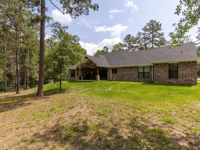 165 Sanctuary Rd, Huntsville, TX 77340 - rear view of property with a lawn, a shingled roof, and brick siding