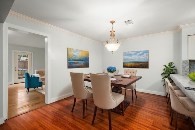 dining space with baseboards, visible vents, wood finished floors, and ornamental molding