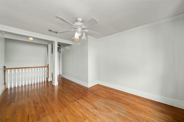 empty room featuring ceiling fan, crown molding, visible vents, baseboards, and hardwood / wood-style floors