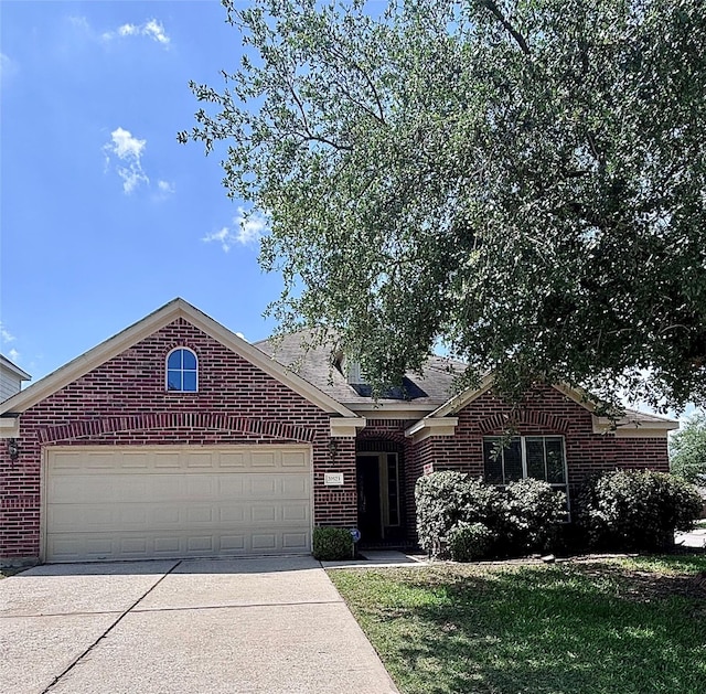 view of front of house featuring a front yard, driveway, an attached garage, and brick siding