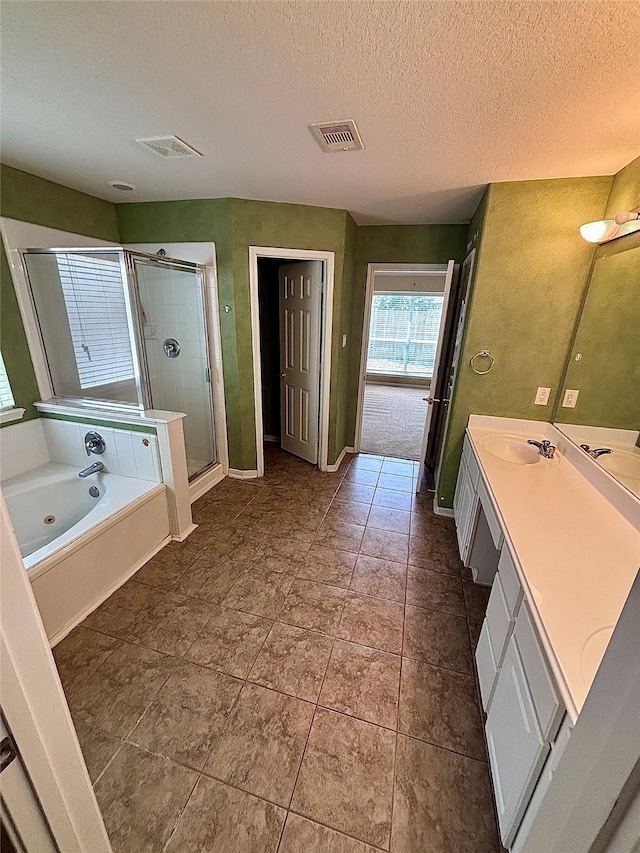 full bathroom featuring a textured ceiling, a shower stall, visible vents, a bath, and vanity