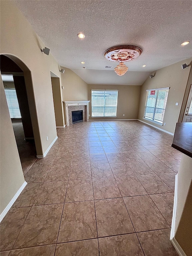unfurnished living room featuring a healthy amount of sunlight, a textured ceiling, and vaulted ceiling