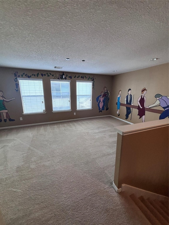 unfurnished living room featuring a textured ceiling, visible vents, carpet flooring, and baseboards