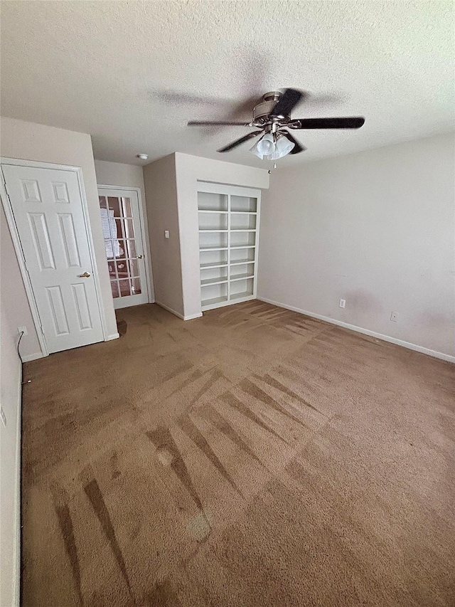 unfurnished bedroom featuring a textured ceiling, carpet flooring, ceiling fan, and baseboards