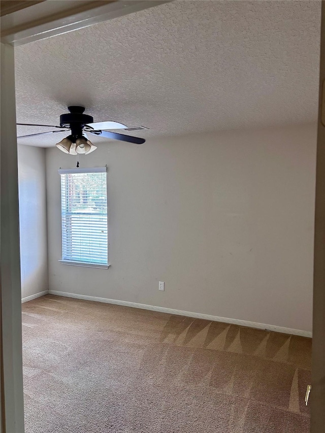 carpeted spare room with baseboards, ceiling fan, and a textured ceiling