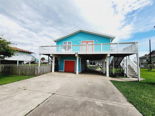 16606 John Davis Rd, Jamaica Beach, TX 77554 - coastal inspired home featuring a garage, a carport, stairs, concrete driveway, and fence