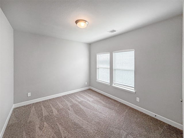 carpeted empty room featuring visible vents and baseboards