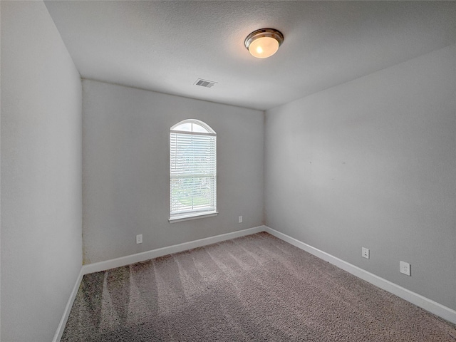 carpeted empty room featuring baseboards and visible vents