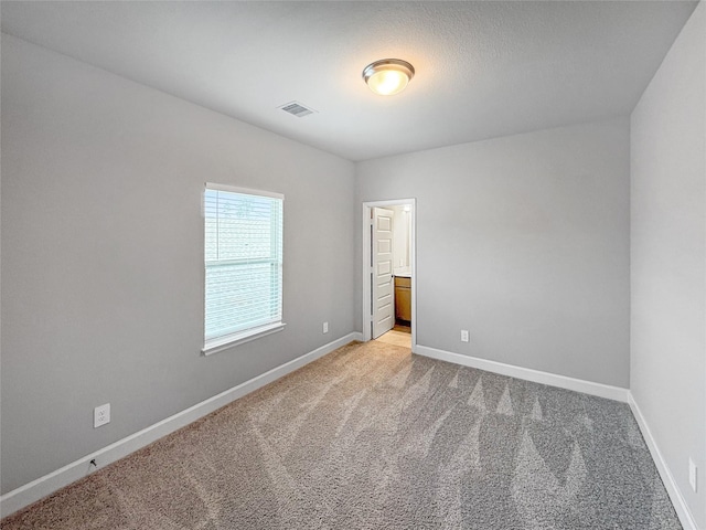 unfurnished room featuring visible vents, baseboards, and light carpet