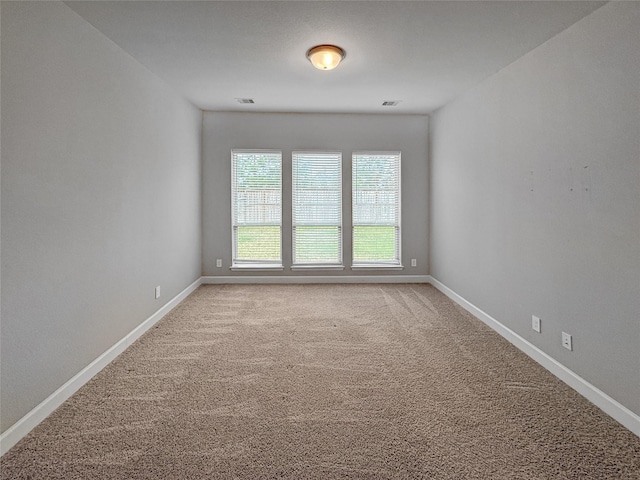 spare room with baseboards and light colored carpet