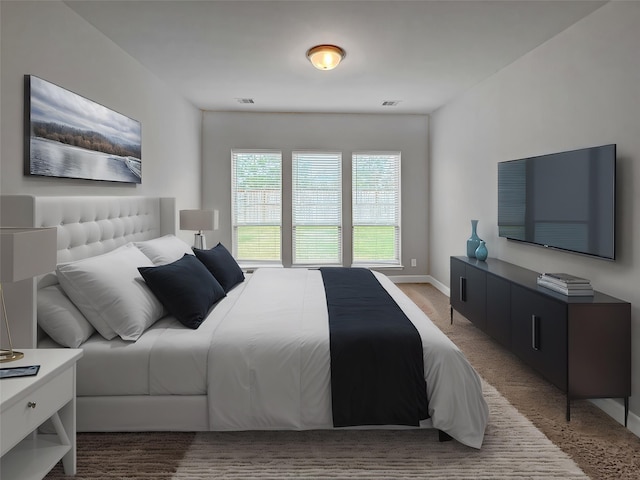 bedroom featuring visible vents, light colored carpet, and baseboards