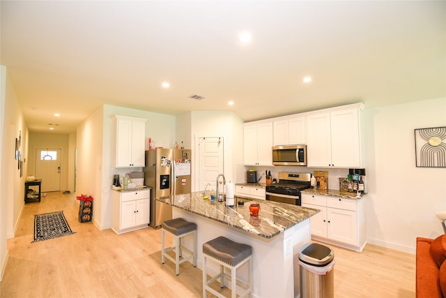 1219 Ricasoli Dr, Richmond, TX 77406 - kitchen with light stone counters, visible vents, stainless steel appliances, light wood-type flooring, and an island with sink