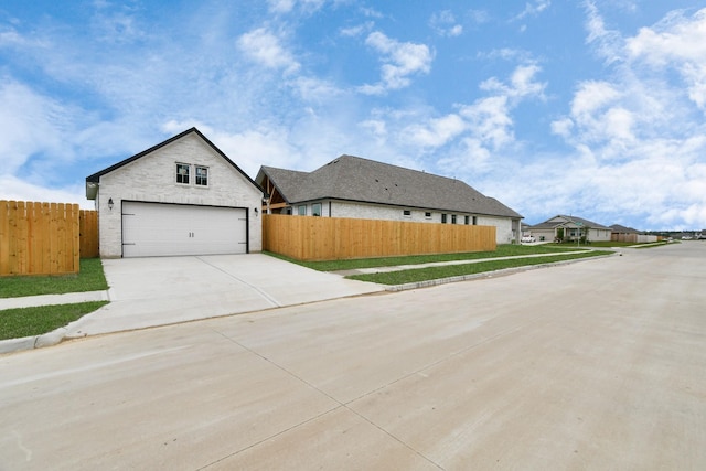 view of front of house featuring fence, concrete driveway, stone siding, and a garage