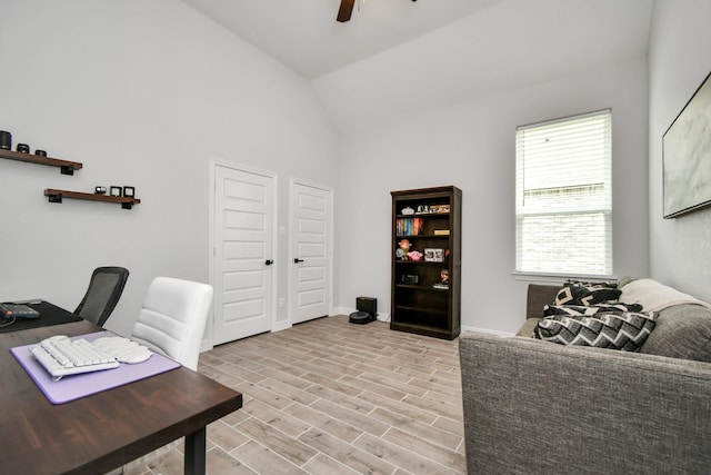office area featuring light wood finished floors, a ceiling fan, lofted ceiling, and baseboards