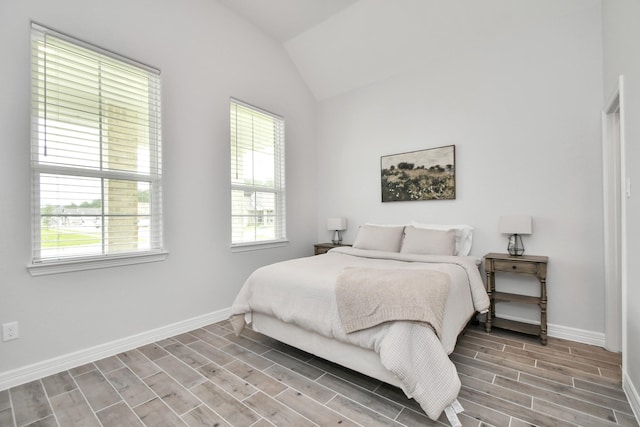 bedroom featuring wood tiled floor, multiple windows, lofted ceiling, and baseboards