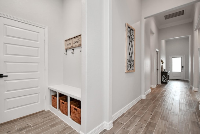 mudroom with ornamental molding, visible vents, light wood-style flooring, and baseboards