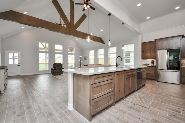 kitchen featuring appliances with stainless steel finishes, a sink, beam ceiling, a ceiling fan, and open floor plan