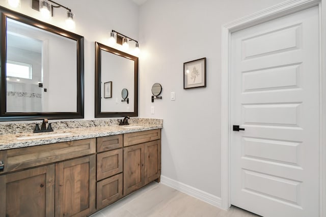 bathroom with double vanity, baseboards, and a sink