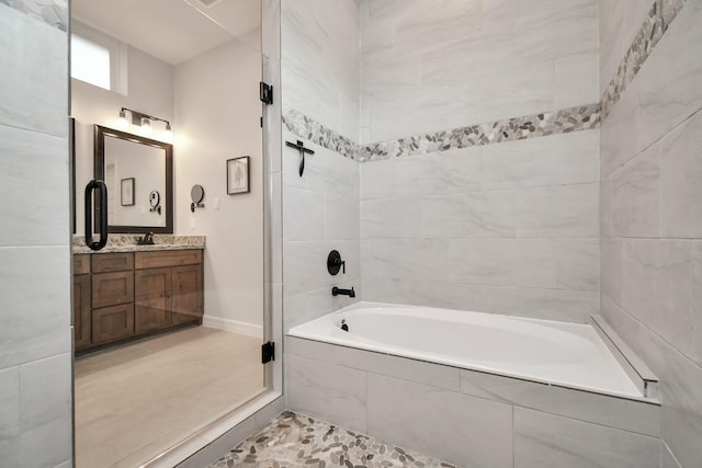 full bath featuring baseboards, tile patterned floors, tiled shower / bath combo, and vanity