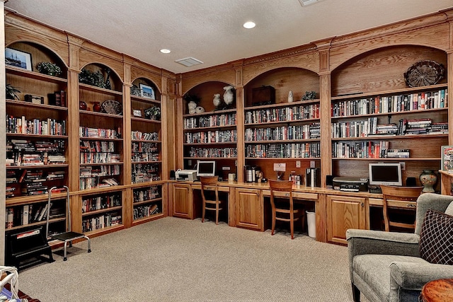 carpeted office space featuring bookshelves, built in study area, a textured ceiling, recessed lighting, and built in features