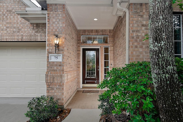 entrance to property with brick siding and an attached garage
