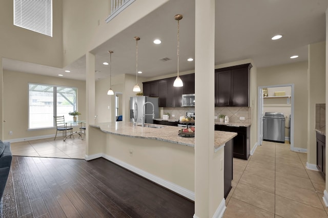 8107 Lockridge Terrace Ln, Cypress, TX 77433 - kitchen featuring decorative backsplash, light stone counters, stainless steel appliances, dark brown cabinets, and baseboards