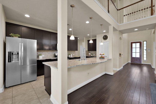 8107 Lockridge Terrace Ln, Cypress, TX 77433 - kitchen with baseboards, light stone countertops, stainless steel refrigerator with ice dispenser, and dark brown cabinetry