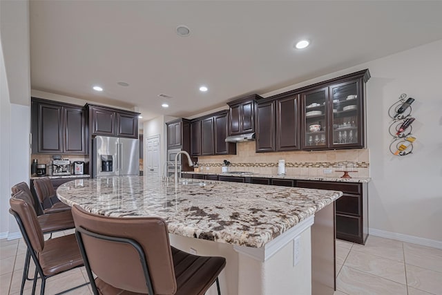 kitchen featuring a sink, tasteful backsplash, under cabinet range hood, and high end fridge