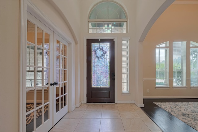 foyer featuring arched walkways, baseboards, and french doors