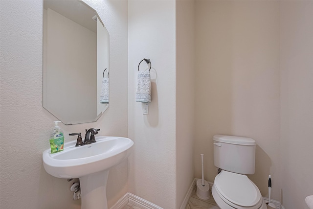 bathroom featuring baseboards and toilet