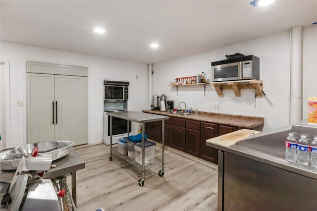kitchen with dark brown cabinetry, stainless steel microwave, open shelves, light wood-type flooring, and wine cooler