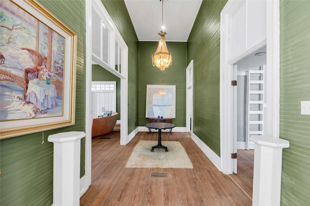 interior space featuring an inviting chandelier, wood finished floors, visible vents, and baseboards