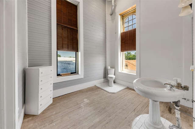bathroom with baseboards, wood finished floors, and toilet