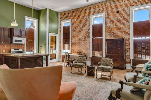 living area featuring brick wall and light wood finished floors