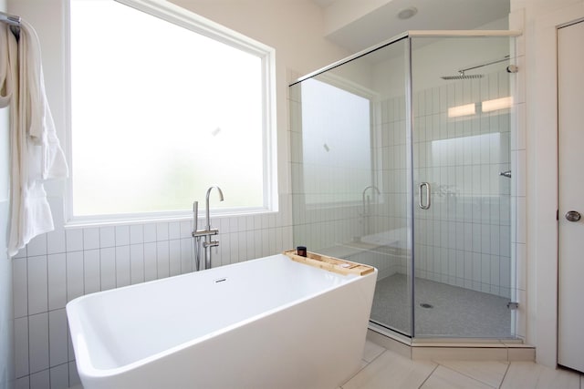 1546 W Tidwell Rd, Houston, TX 77091 - full bath featuring a shower stall, a freestanding bath, tile patterned flooring, and tile walls