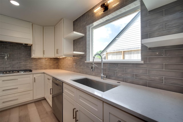 kitchen featuring a sink, gas cooktop, dishwasher, light wood finished floors, and backsplash