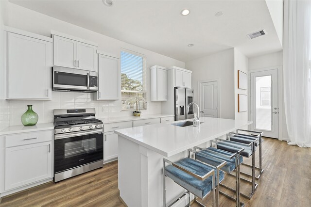 1207 Highland Vineyard Ln, Houston, TX 77091 - kitchen featuring wood finished floors, appliances with stainless steel finishes, a kitchen bar, a sink, and visible vents