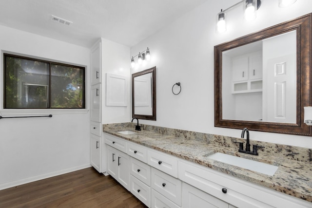 bathroom featuring a sink, baseboards, wood finished floors, and visible vents