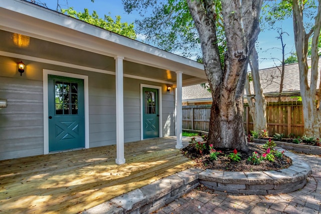 view of exterior entry featuring a wooden deck and fence