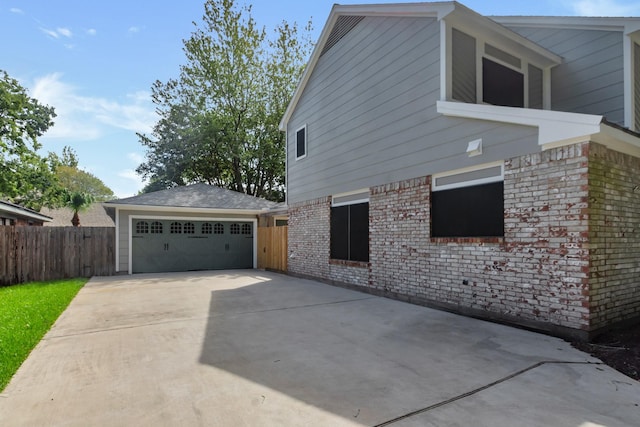 view of side of property with fence, brick siding, and an outbuilding