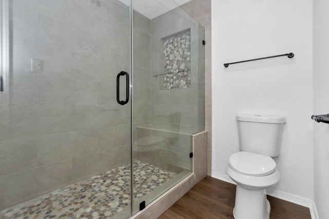 full bath featuring toilet, a stall shower, wood finished floors, and baseboards