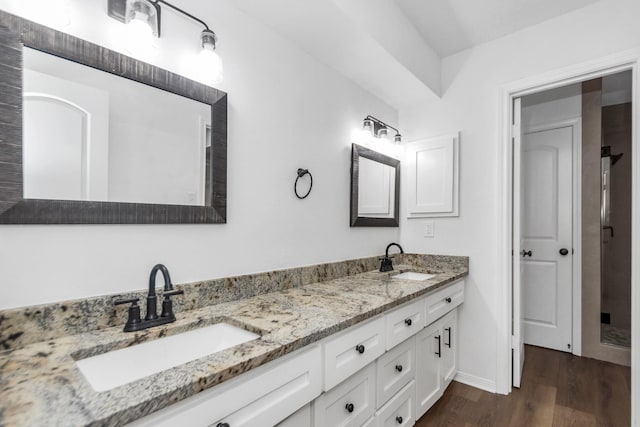 full bathroom featuring double vanity, wood finished floors, baseboards, and a sink