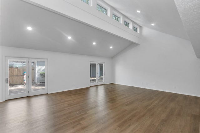unfurnished living room with french doors, baseboards, recessed lighting, wood finished floors, and high vaulted ceiling