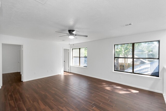 empty room with a ceiling fan, visible vents, baseboards, and dark wood finished floors