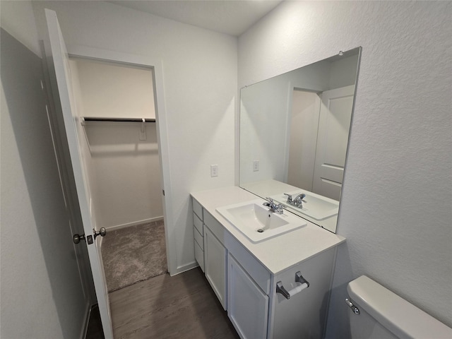 bathroom with wood finished floors, toilet, a textured wall, and vanity